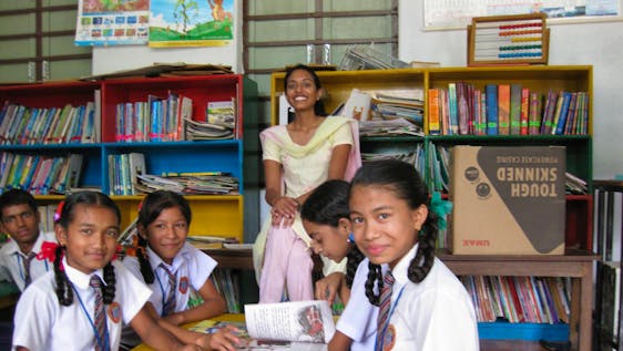 Helping students in a library of a Community school.